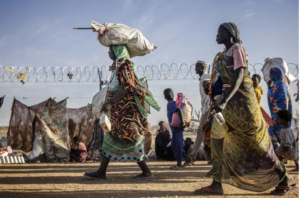 Sudanese refugees and South Sudanese returnees who have fled from the war in Sudan carry their belongings while arriving at a Transit Centre [File: Luis Tato/AFP]