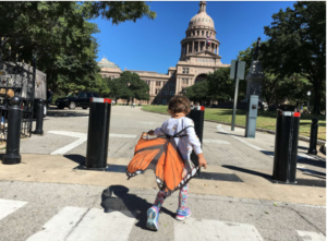 little girl with butterfly backpack runs toward the capital